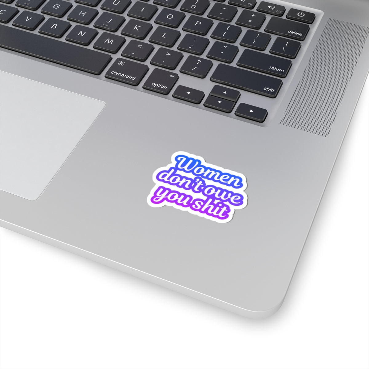 Laptop with a sticker reading 'Women don't owe you shit' on a white background