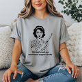 Gray  t-shirt featuring a vintage-style black line illustration of a 1950s housewife in a polka dot dress holding a large kitchen knife, with the text: “Oh that’s just my emotional support knife.”