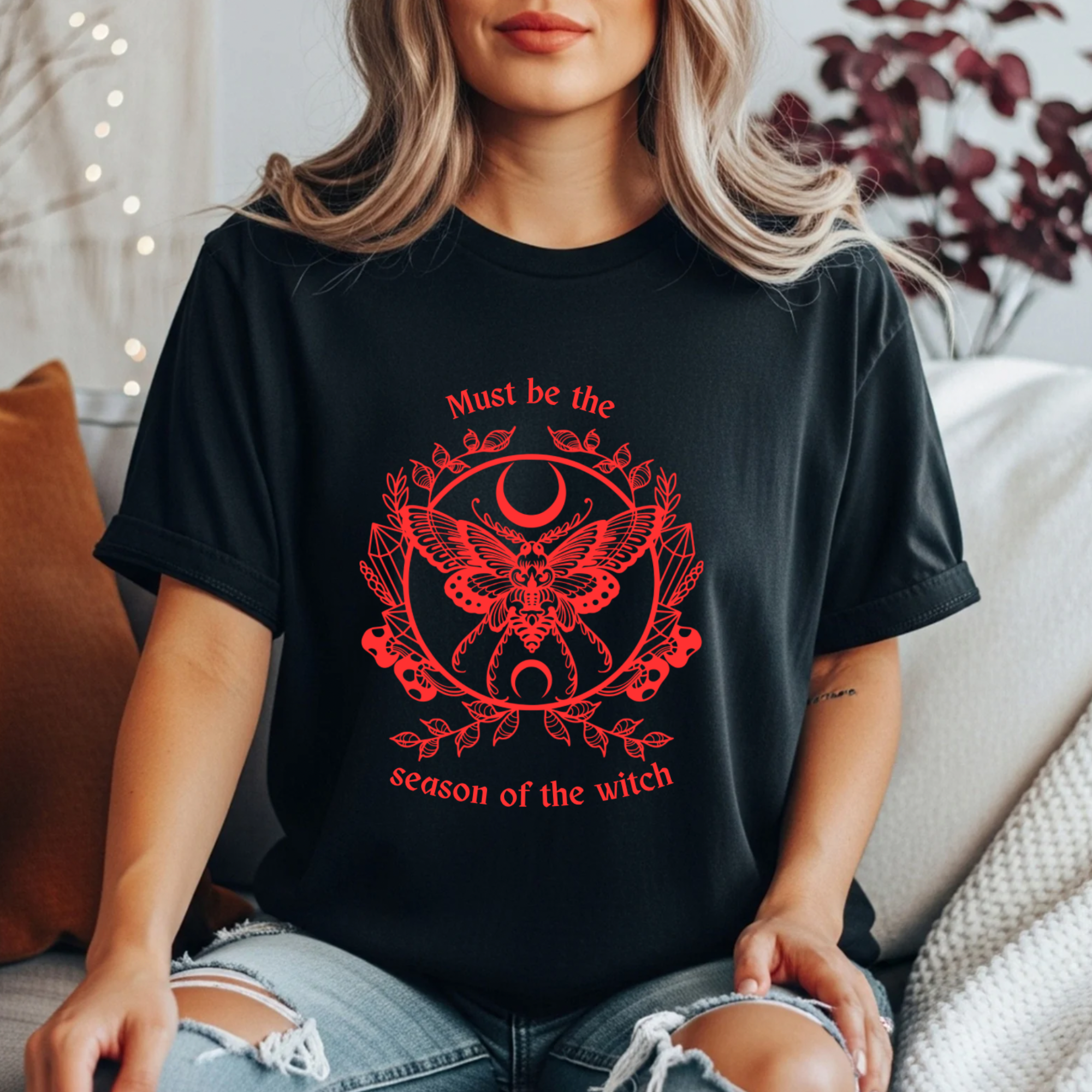 Women’s  black witchy t shirt with bold red text reading “must be the season of the witch” with a moth, circle of crystals and moon graphic. 